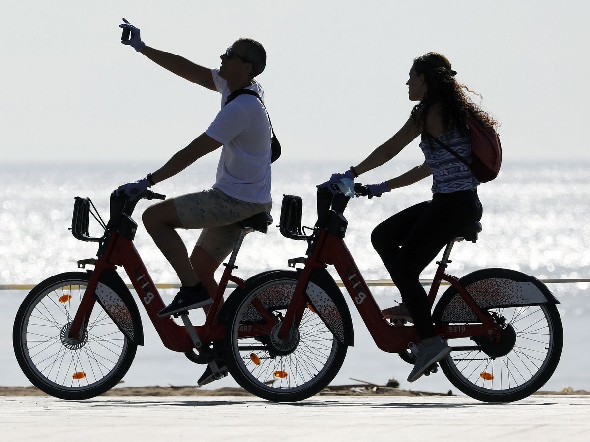 Foto: Barceloneses dando un paseo por la playa en bicicleta. (EFE)