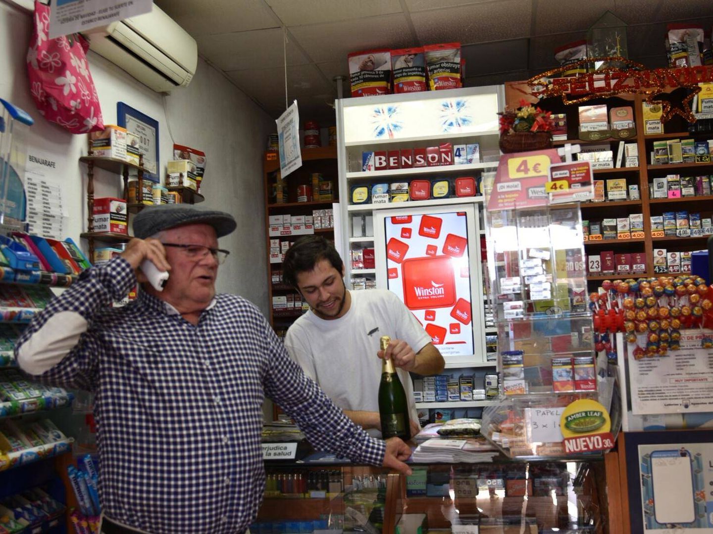 Pepe hablando por teléfono, junto a Douglas, el empleado de la administración de lotería. (Toñi Guerrero)