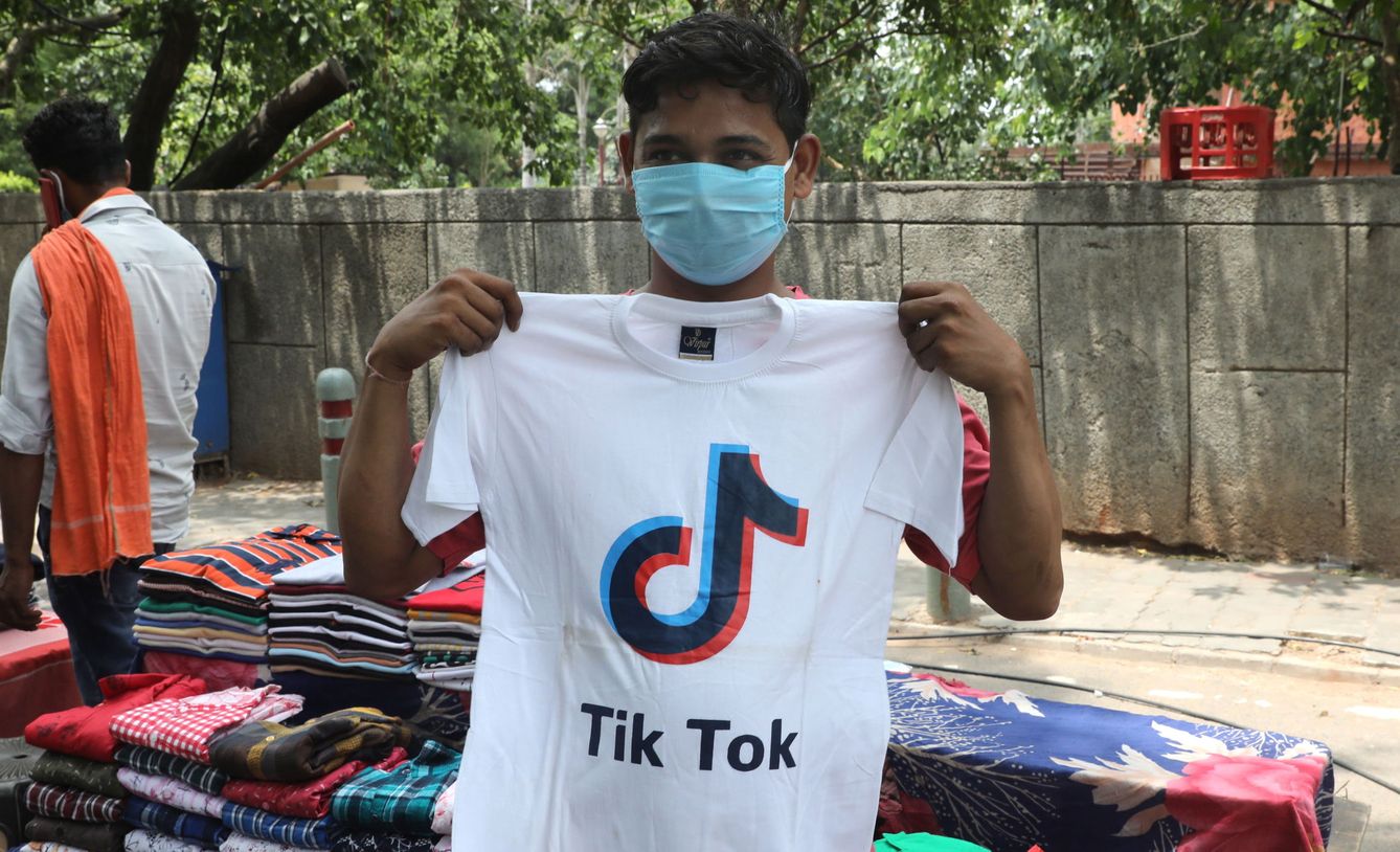 Un vendedor de camisetas en Delhi (India) muestra una con el logo de TikTok. (Reuters)