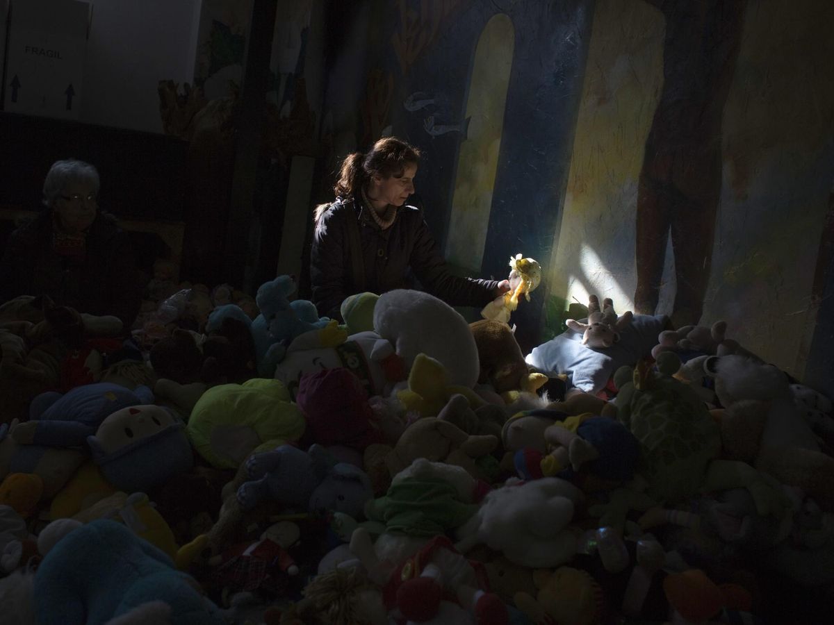 Foto: Una mujer sostiene una muñeca durante una distribución de juguetes donados en Madrid. (Reuters)