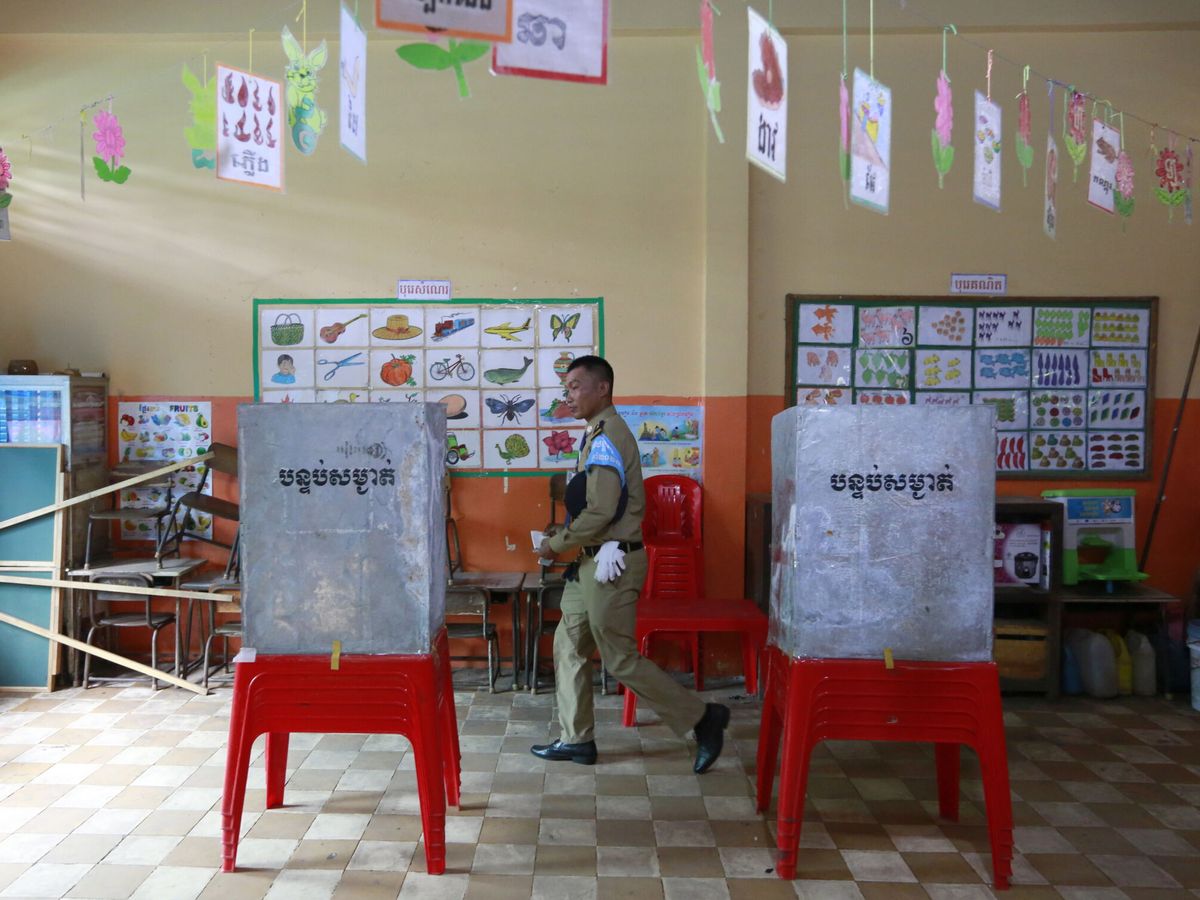 Foto: Un oficial de policía sostiene su voto mientras vota en un colegio electoral en Camboya. (EFE/Kith Serey)