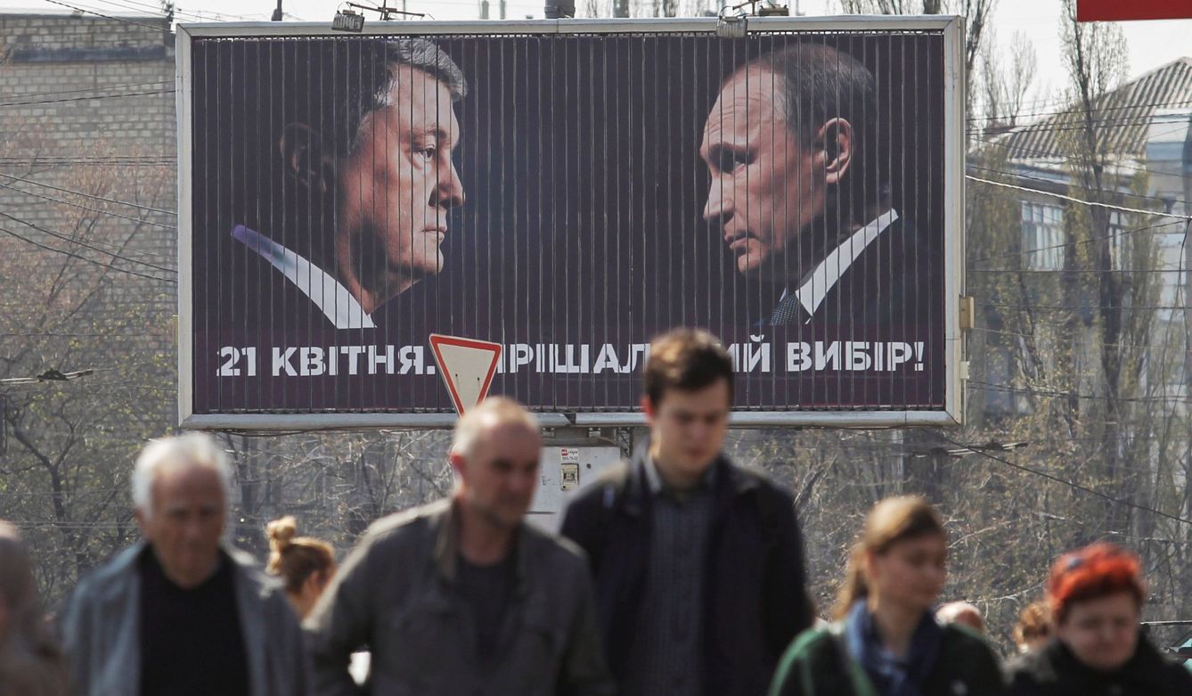 Viandantes caminan junto a un cartel electoral en el que aparecen Petro Poroshenko (i), ante el presidente ruso, Vladímir Putin (d). 