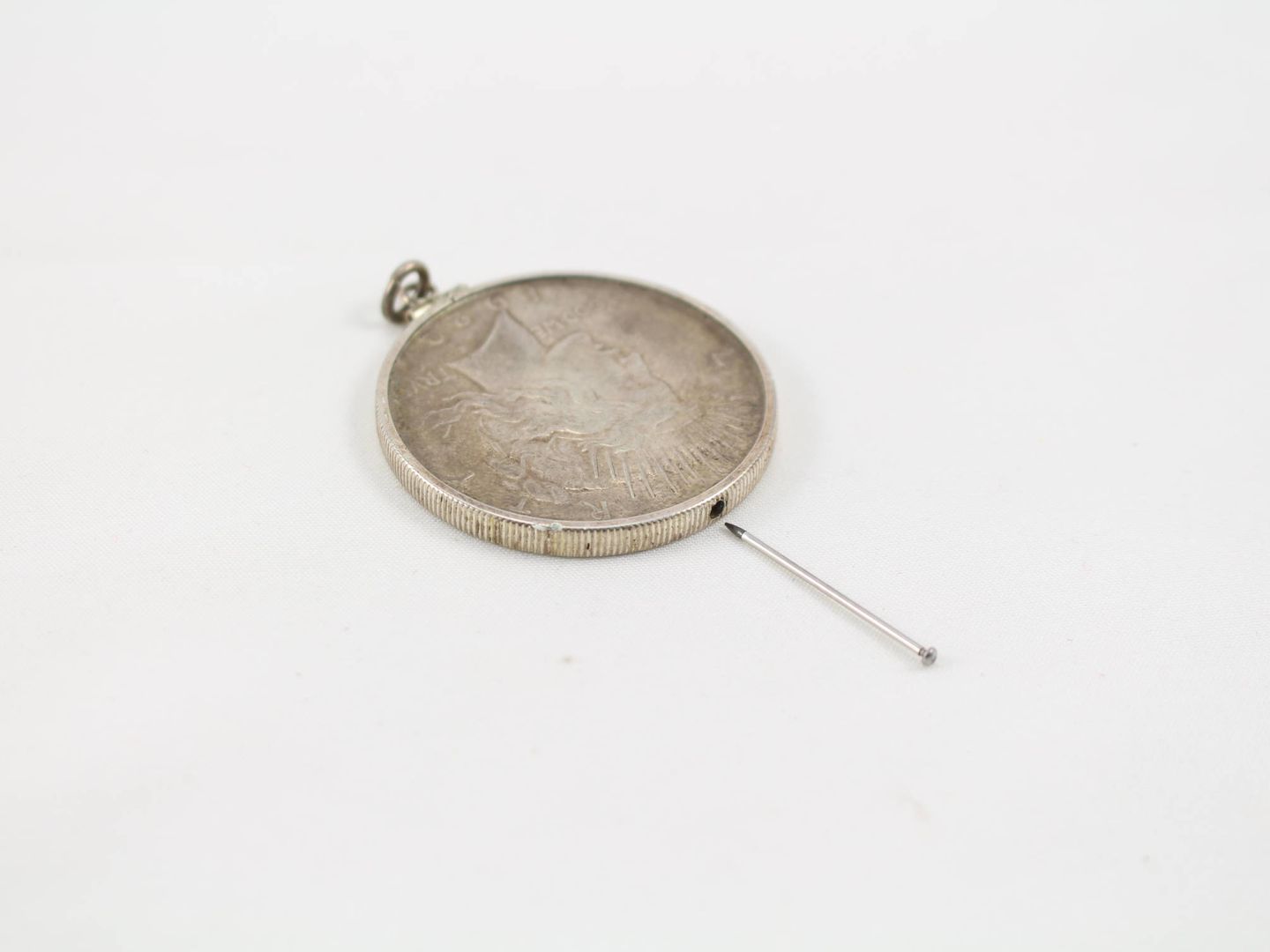 Un dólar de plata con un alfiler para el suicidio como el que llevaba Gary Powers (Colección de Keith Melton en el International Spy Museum)
