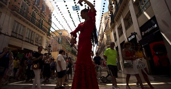 Foto: Una mimo vestida con traje de flamenca actúa en la calle Larios, en la Feria del Centro de Málaga. (EFE)
