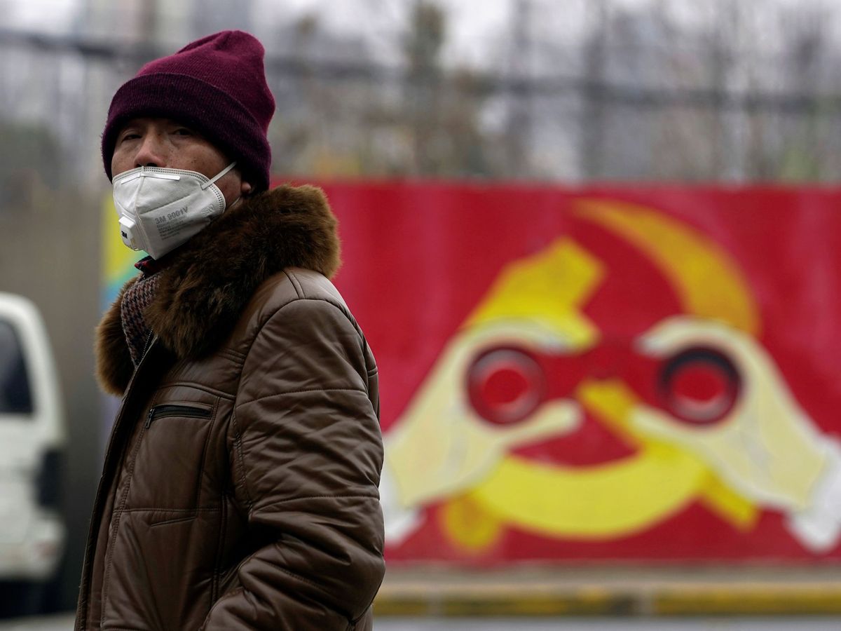 Foto: Un hombre porta una mascarilla frente a una imagen modificada del emblema del PCC. (Reuters)