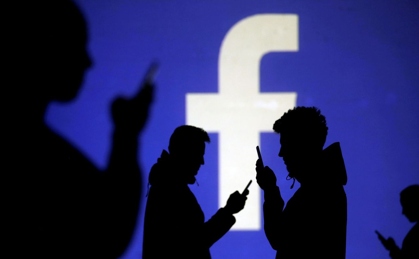 FILE PHOTO: Silhouettes of mobile users are seen next to a screen projection of Facebook logo in this picture illustration taken March 28, 2018.  REUTERS Dado Ruvic Illustration File Photo