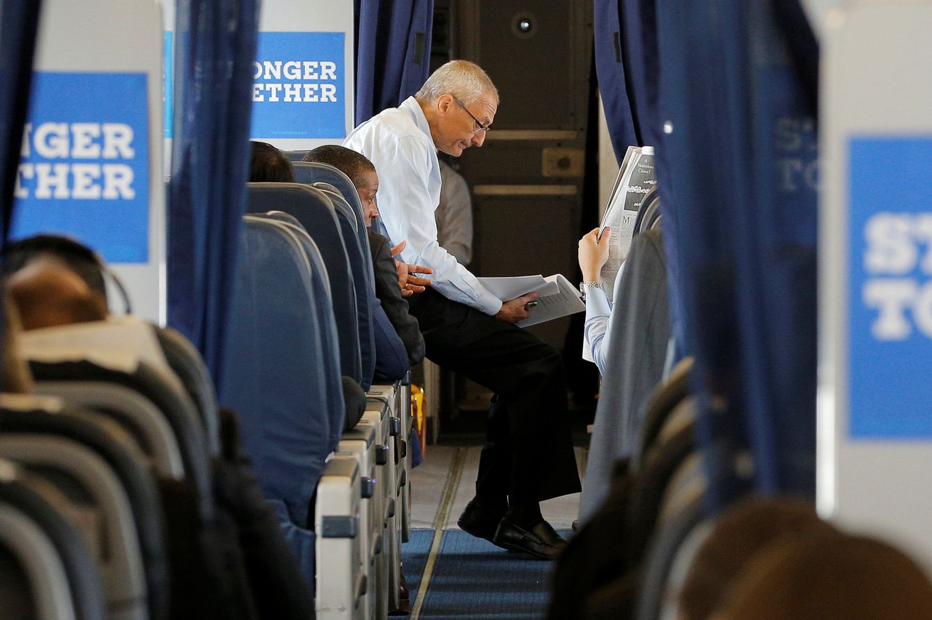 John Podesta, jefe de campaña de Hillary Clinton, lee la prensa en un viaje en plena campaña electoral. (Reuters)