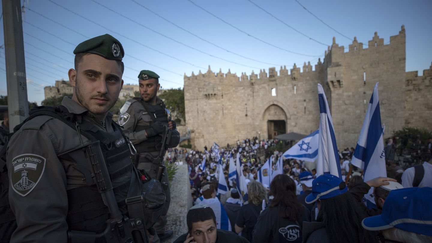 Policías israelíes montan guardia mientras activistas israelíes agitan banderas del país frente a la Puerta de Damasco en la ciudad vieja de Jerusalén, el 13 de mayo de 2018. (Reuters)