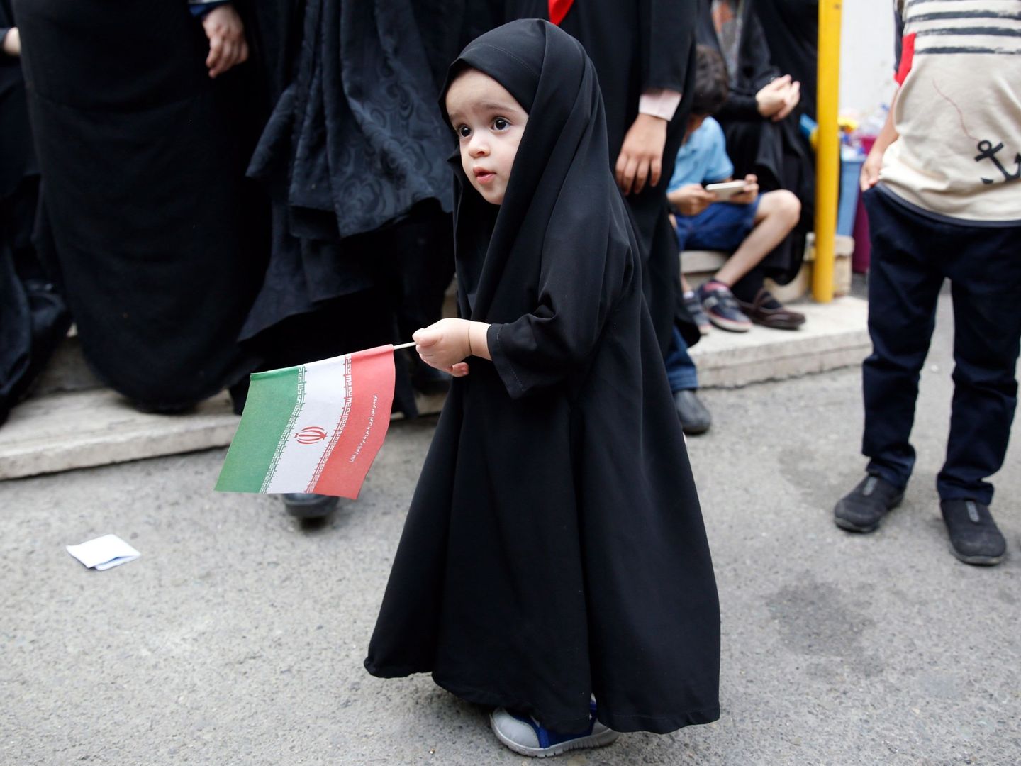 Una niña sostiene la bandera de Irán en una ceremonia de 2019 en apoyo al código de vestimenta obligatorio. (EFE)