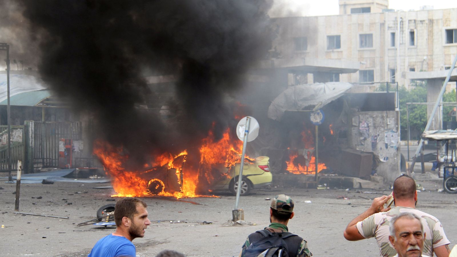 Foto: Un soldado sirio y civiles observan la escena de un atentado en Tartús, Siria, el 23 de mayo (Reuters).