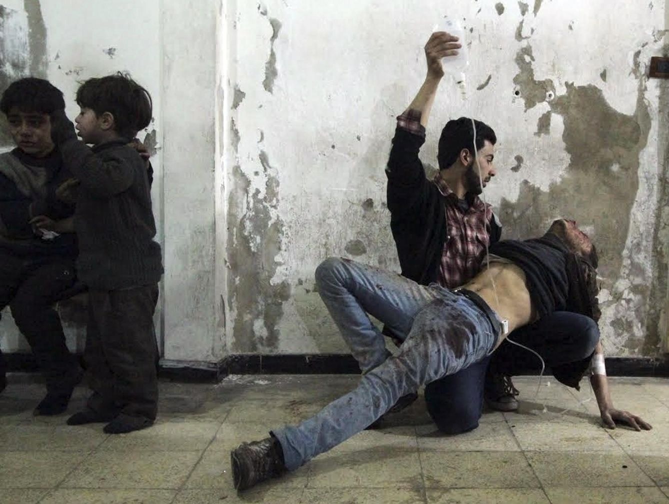Un hombre da asistencia médica a un herido en un bombardeo del régimen mientras dos niños esperan a ser atendidos en Damasco. (Reuters)