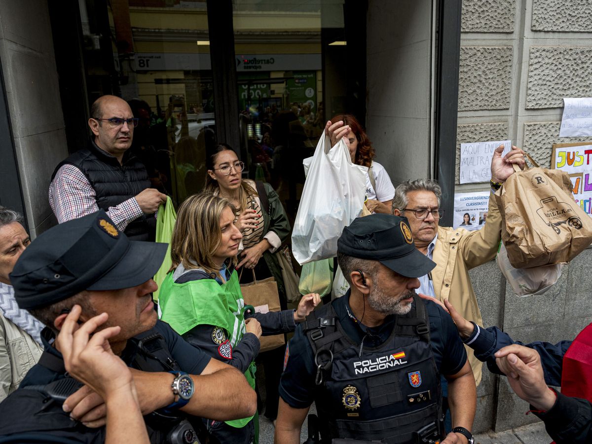 Foto: Varias personas intentan hacer llegar comida a los representantes de los sindicatos de Justicia encerrados en el Ministerio. (EFE/ Fernando Villar)