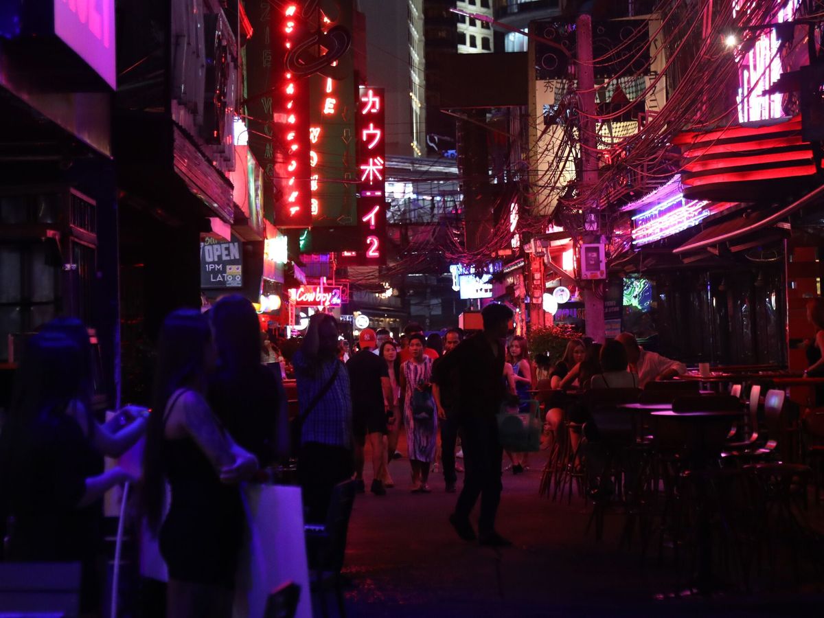 Foto: Los turistas pasan junto a los bares nocturnos de Soi Cowboy, un barrio rojo de Bangkok. (EFE/Narong Sangnak)