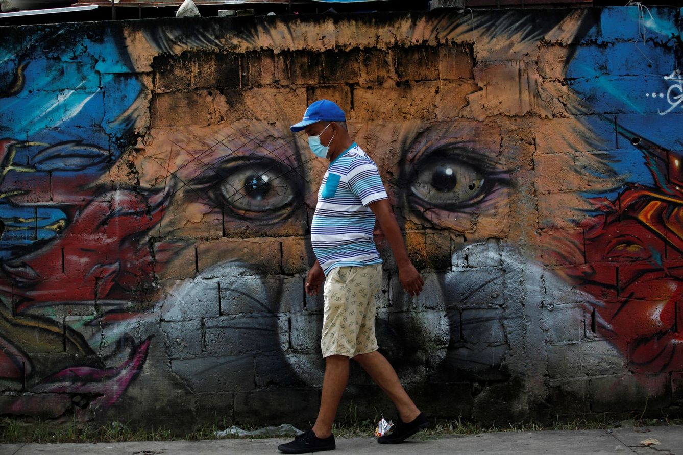 Un residente camina con un tapabocas frente a un mural durante una jornada de desinfección en el barrio del Chorrillo. (EFE)