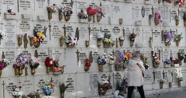 Foto: Una mujer pasa junto a una pared de columbarios en el cementerio de La Almudena de Madrid. (EFE)