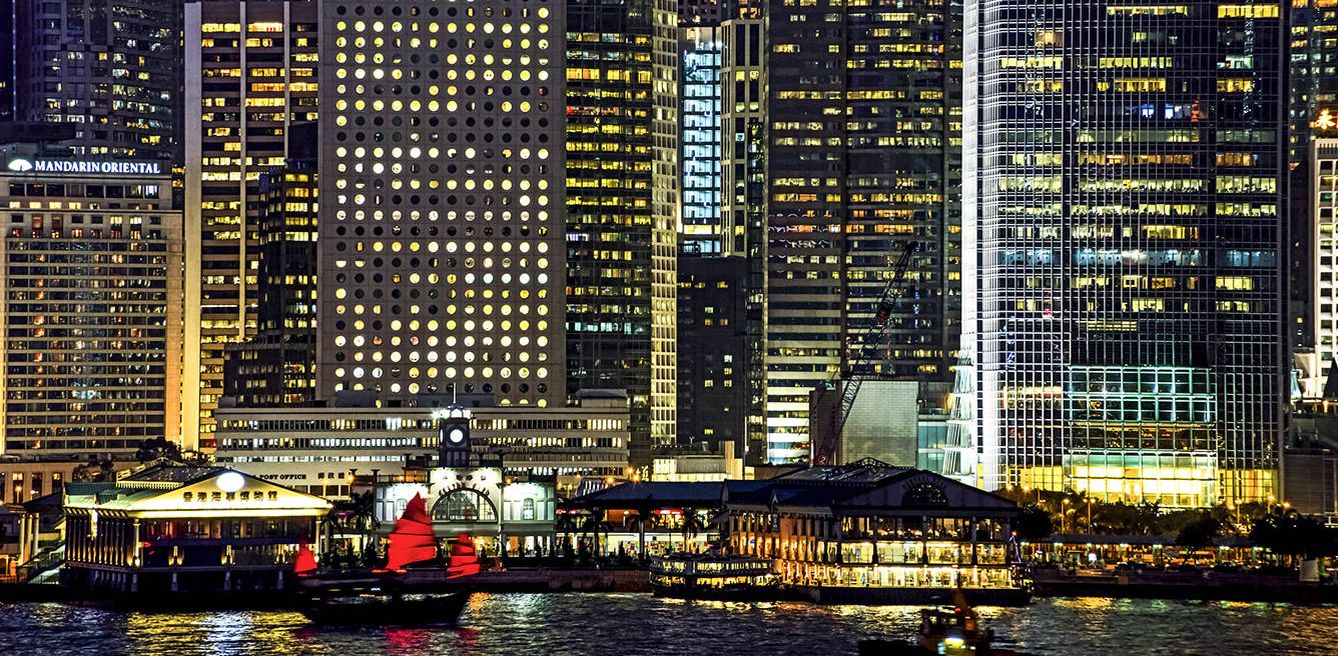 En la fotografía, una embarcación con las características velas rojas navega a los pies de los rascacielos de Hong Kong.