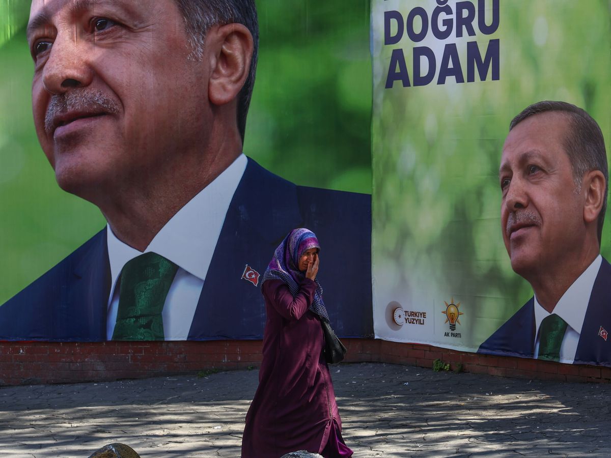 Foto: Una mujer camina delante de las fotos del presidente turco Recep Tayyip Erdogan en Estambul. (EFE / Sedat Suna)