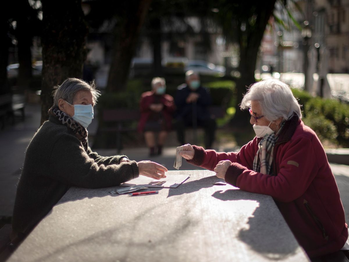 Foto: Dos mujeres con mascarillas juegan a las cartas en un parque de Ourense. (EFE/Brais Lorenzo)