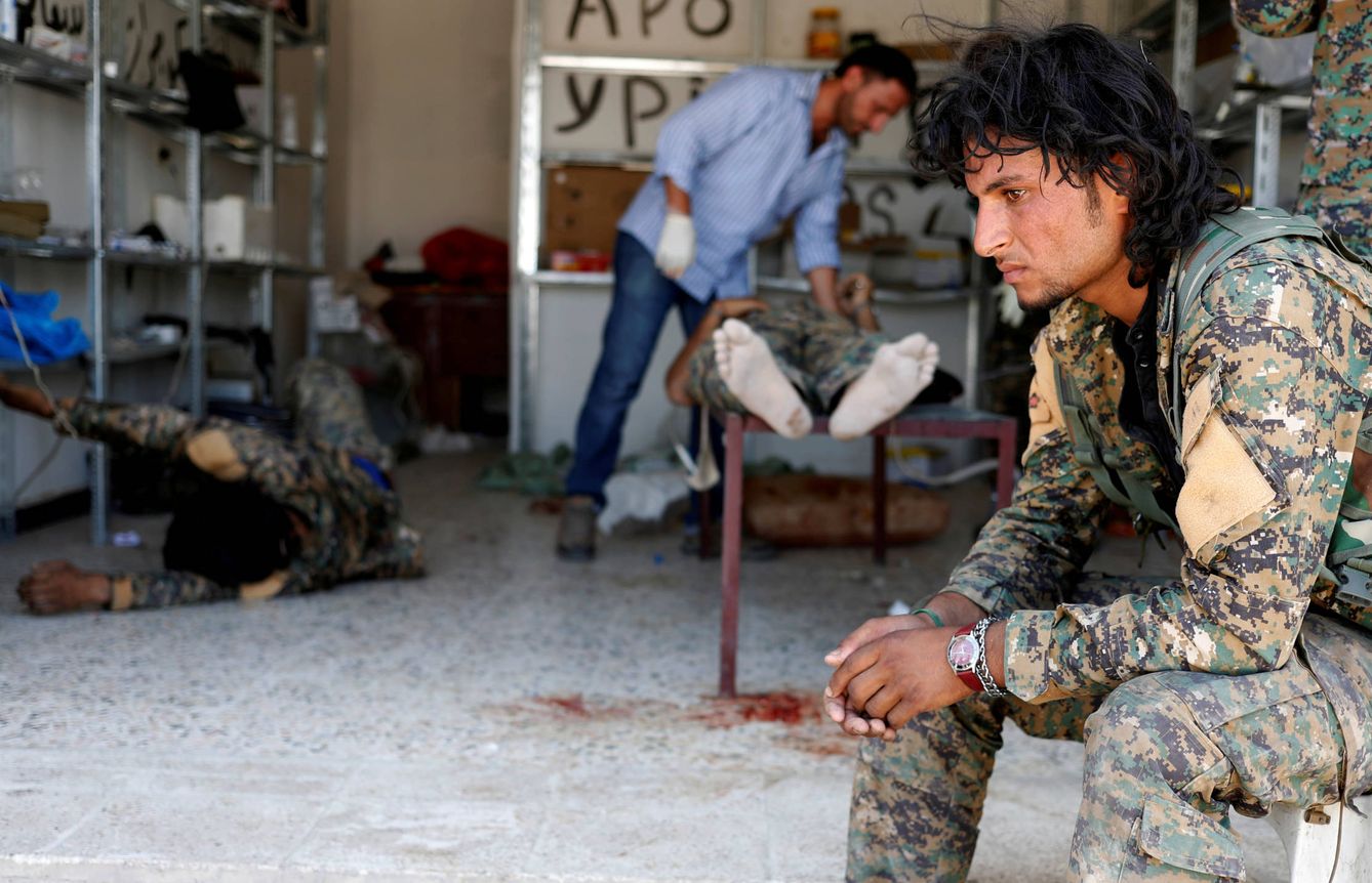 Un miliciano de las Fuerzas Democráticas Sirias ante varios camaradas heridos en combates contra ISIS, en Raqqa. (Reuters) 
