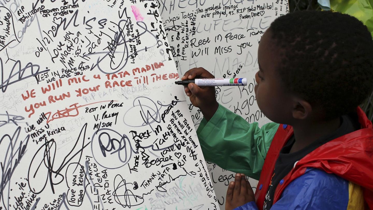 Un niño escribe un mensaje a las puertas de la casa de Mandela en Johannesburgo (Reuters).