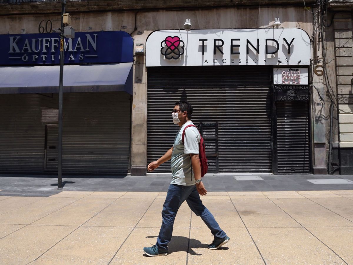 Foto: Un hombre camina frente a un par de locales comerciales cerrados. (EFE)