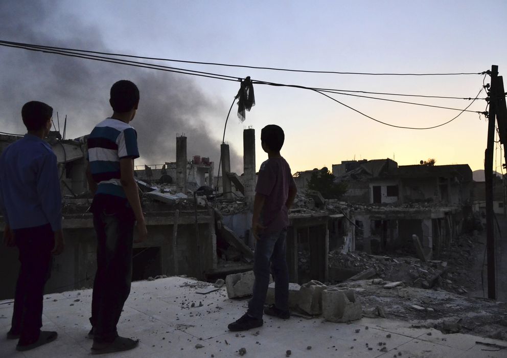 Foto: Un grupo de menores observa una columna de humo tras una explosión en el suburbio de Ghouta, Damasco (Reuters).
