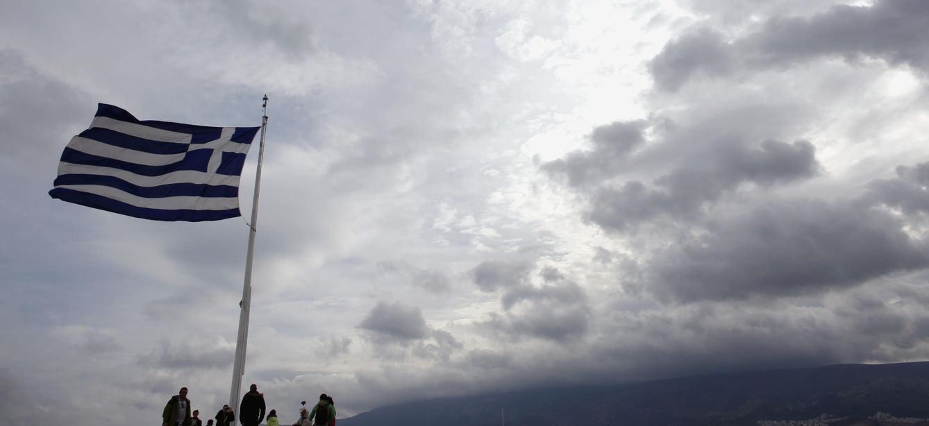 Foto: Turistas bajo una bandera griega en la cima de la Acrópolis, en Atenas, el 22 de febrero (Reuters).