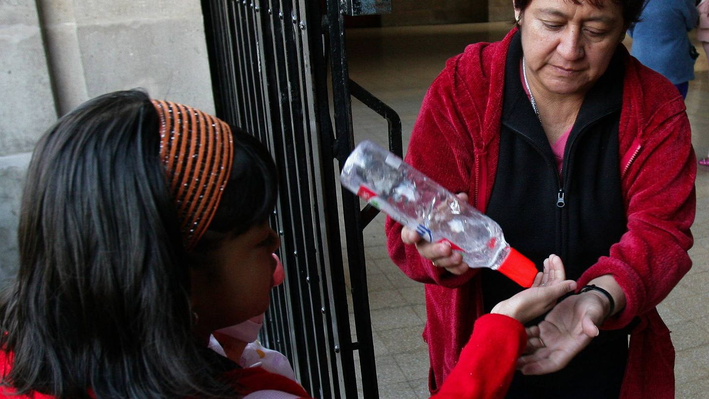 Una profesora proporciona gel desinfectante a una alumna en un colegio (EFE/Isaac Esquivel)