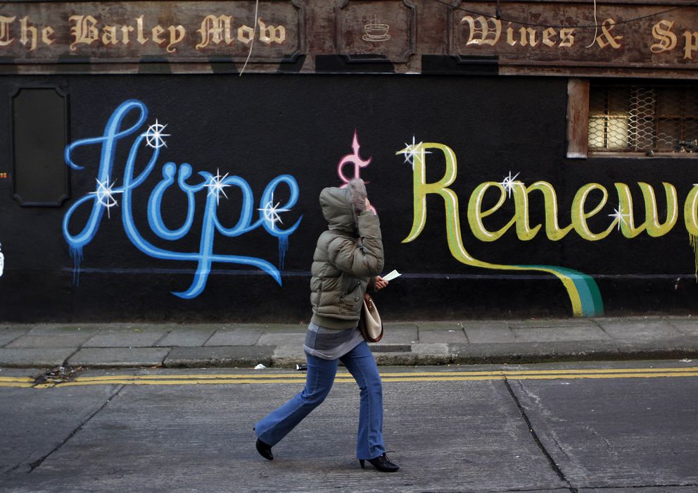 Foto: Una mujer pasa ante una pintada en Dublín que reza: "Esta ciudad necesita esperanza y renovación" (Reuters).