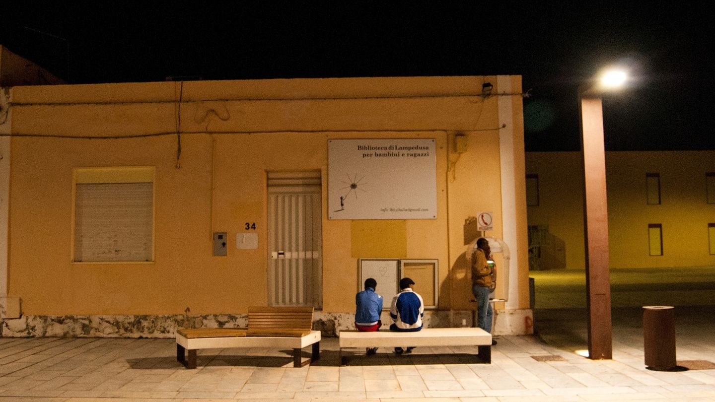 Unos migrantes guardan cola para llamar por teléfono en  Via Roma, Lampedusa. (Manuel Tori)