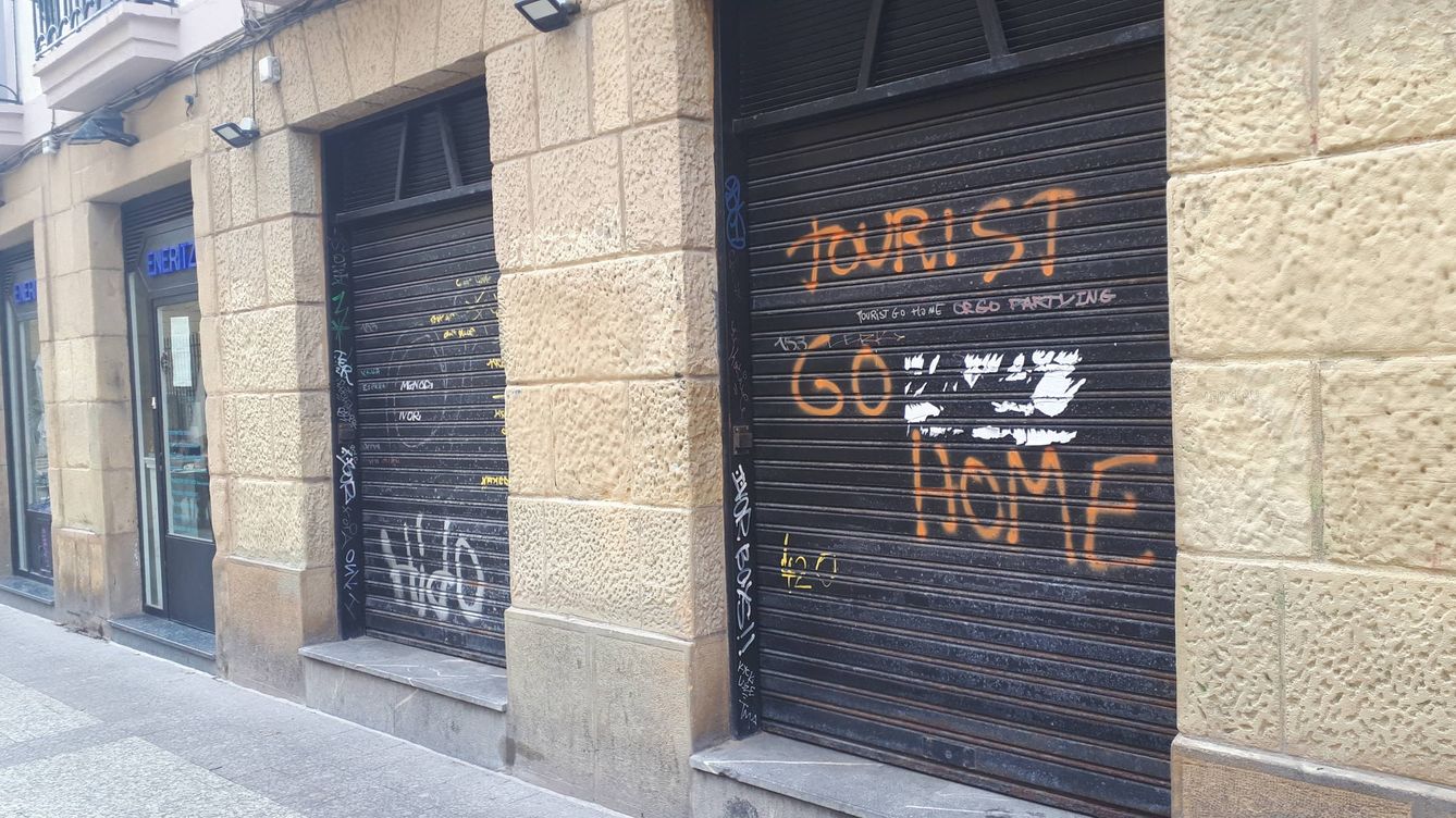 Una pintada 'vieja' en la persiana de un bar cerrado de San Sebastián pide a los turistas irse a su 'casa'. (EC)