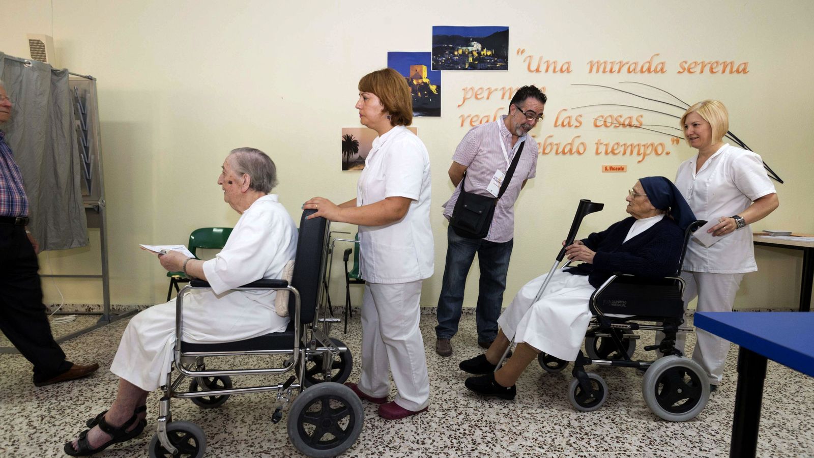 Foto: Dos personas son llevadas en silla de ruedas para ejercer su derecho al voto en las elecciones generales. (Efe) 