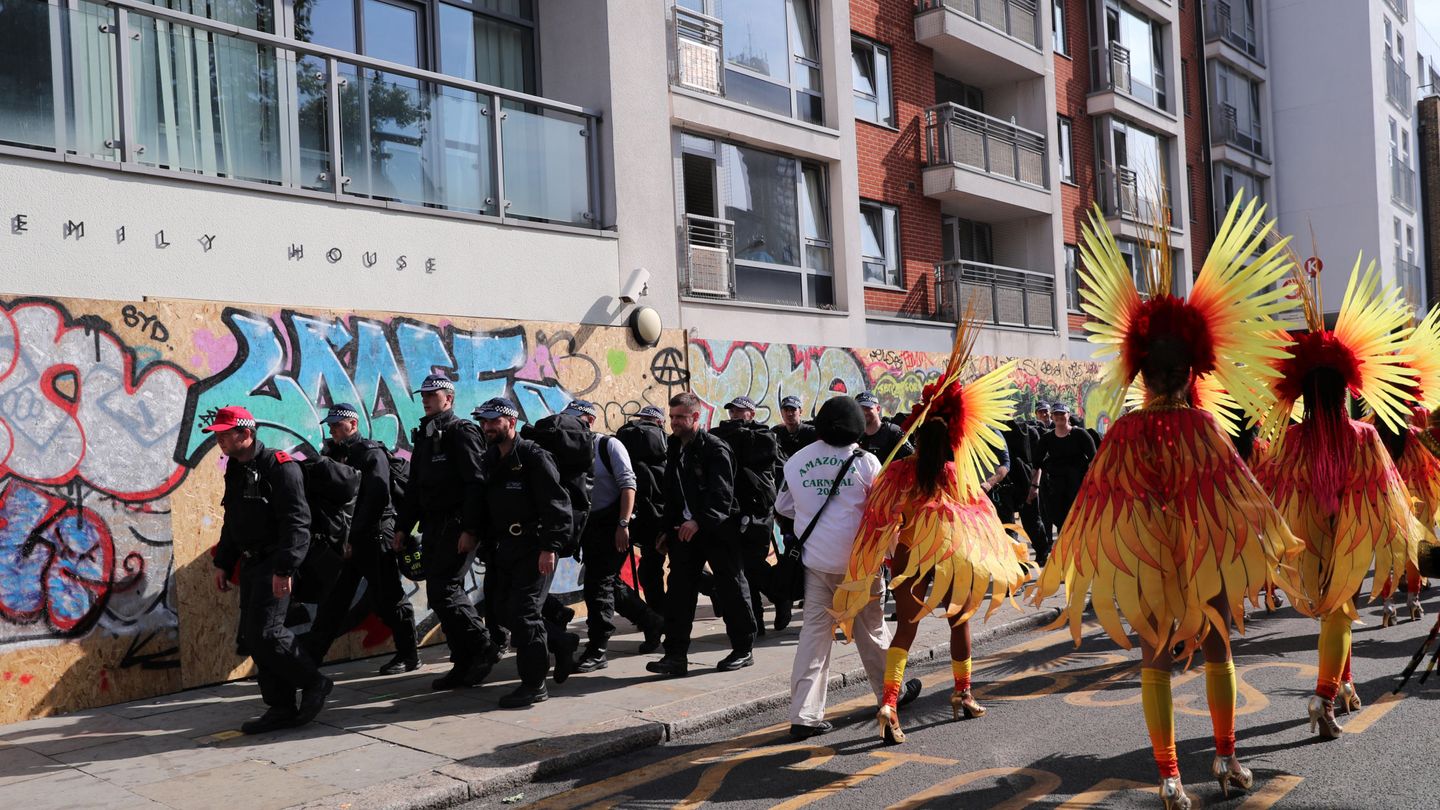 Oficiales de policía pasan ante participantes en el Carnaval de Notting Hill, en Londres. (Reuters)