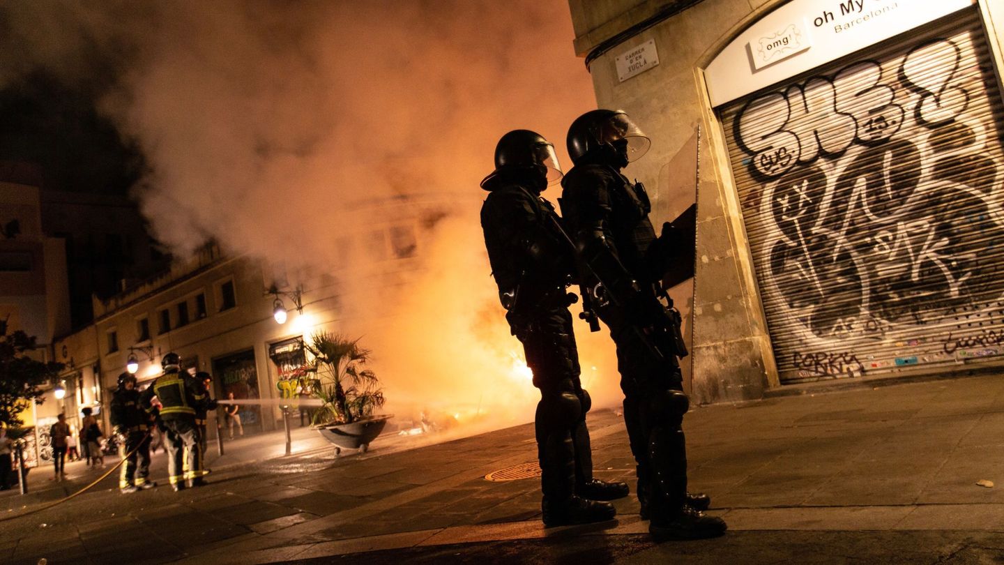 Dos agentes de los Mossos durante los disturbios en Barcelona. (EFE)
