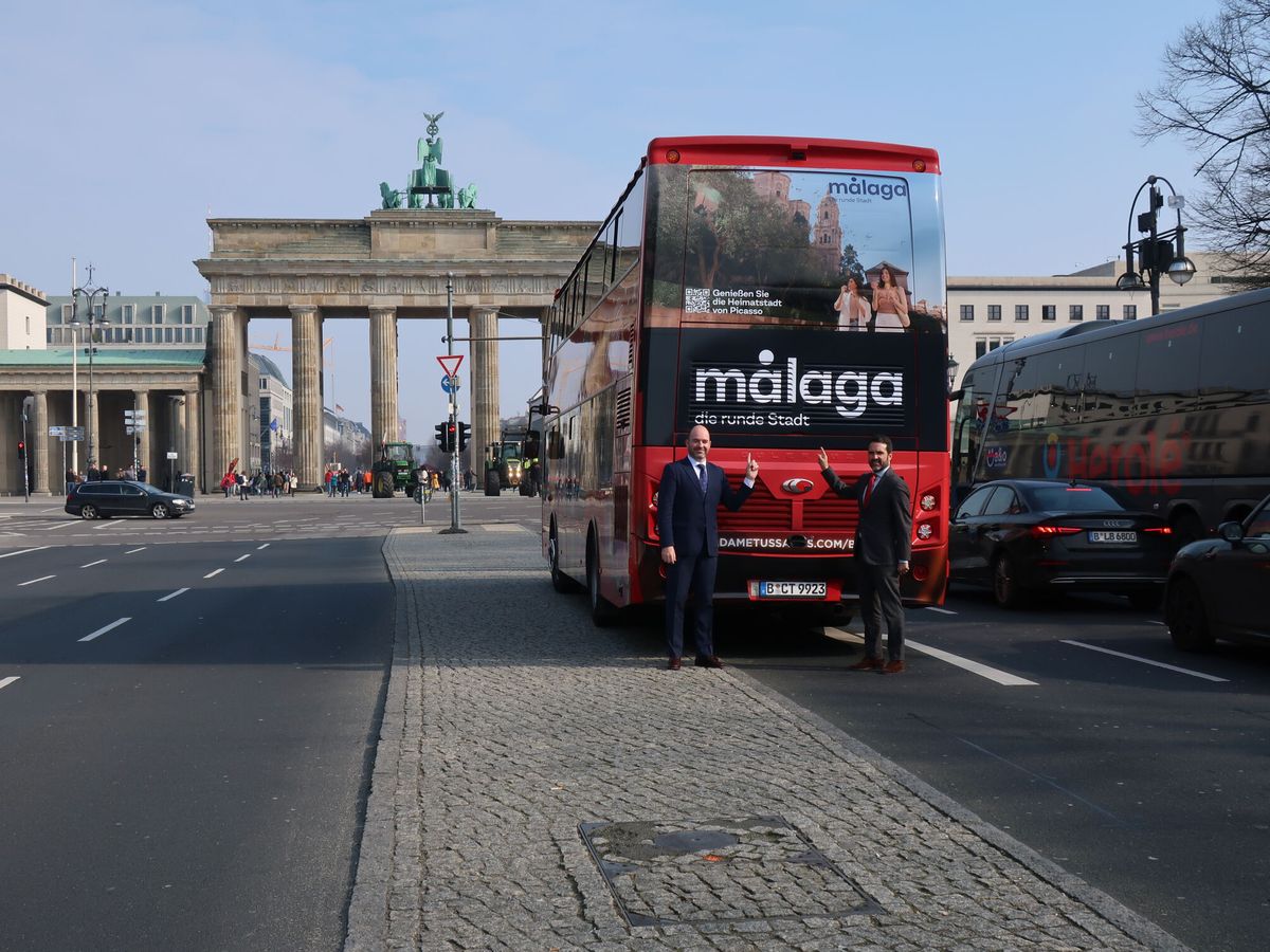 Foto: Dos representantes del Ayuntamiento de Málaga, con un autobús promocional frente a la Puerta de Brandemburgo. (EFE/José Manzaneque)