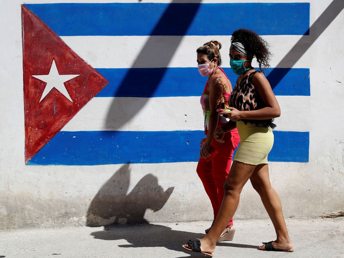 Foto: Dos mujeres caminan frente a un graffiti de la bandera cubana, en La Habana, Cuba. (EFE)