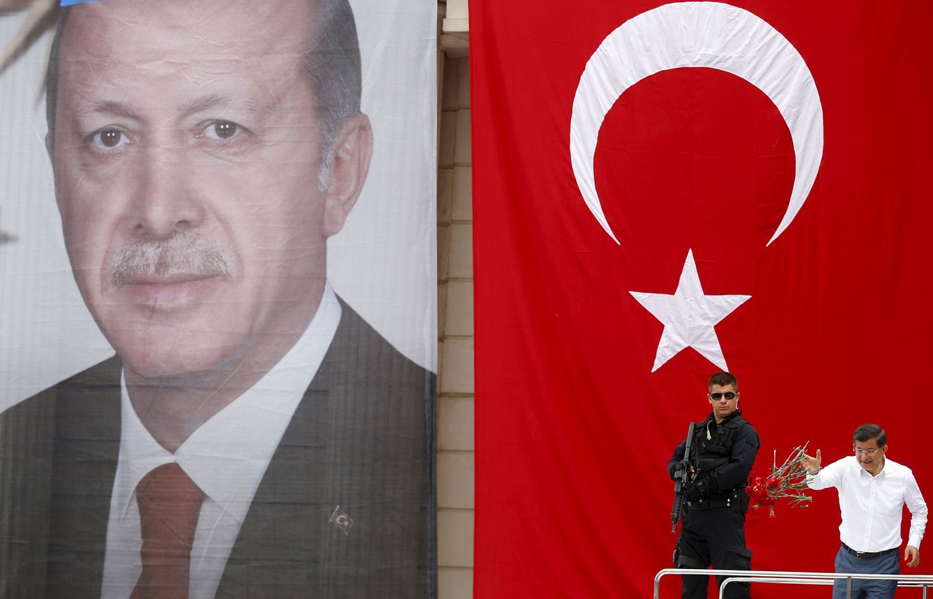 Ahmet Davutoglu arroja claveles a sus seguidores frente a un retrato gigante de Erdogan durante un mitin político en Estambul, en junio de 2015 (Reuters) 