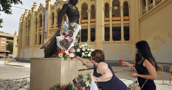 Foto: Dos señoras ponen velas ante la estatua de Dámaso González, en Albacete. (EFE) 
