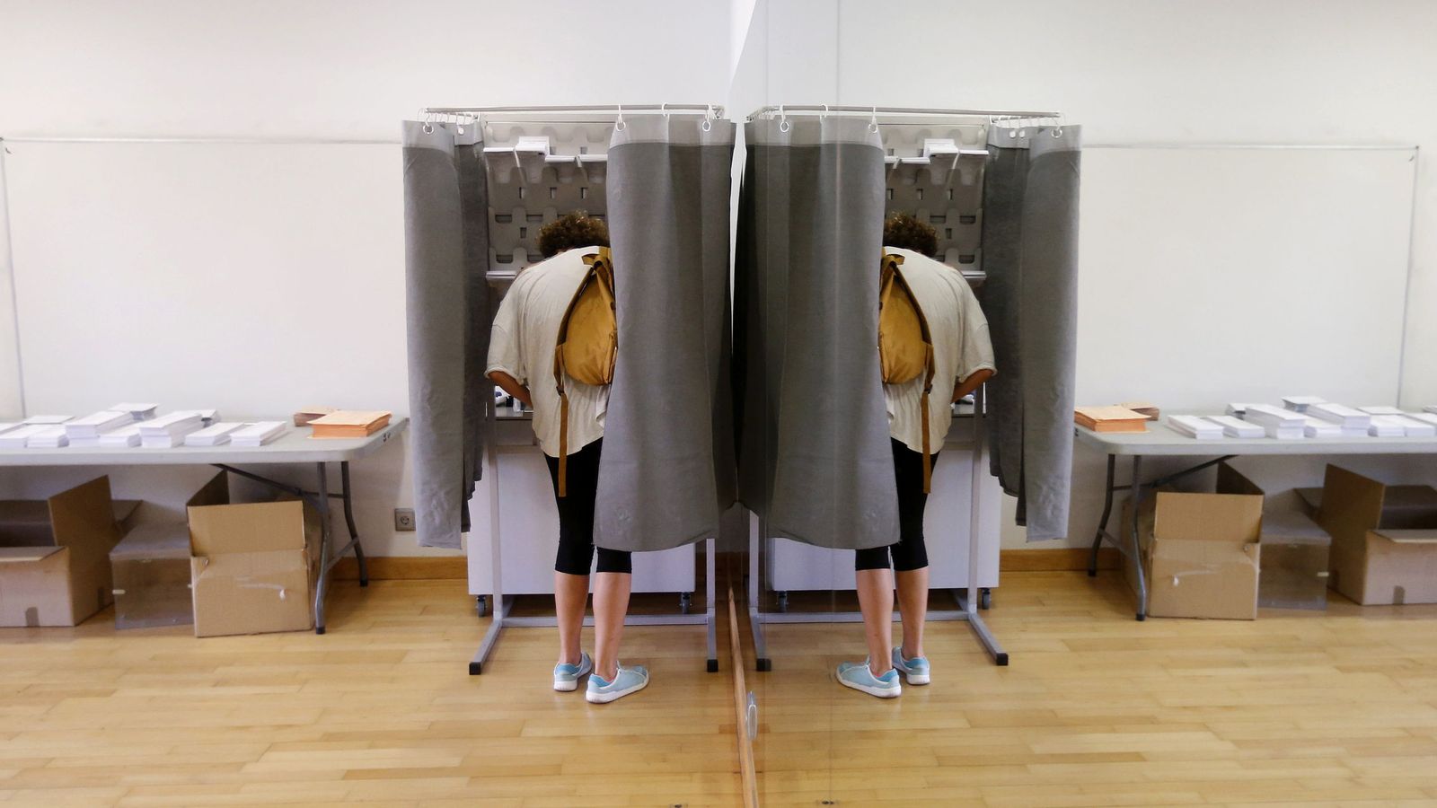 Foto: Un votante, con su imagen reflejada en un espejo, elige su papeleta en un colegio electoral de Pozuelo, en Madrid, en las generales del 26-J de 2016. (EFE)