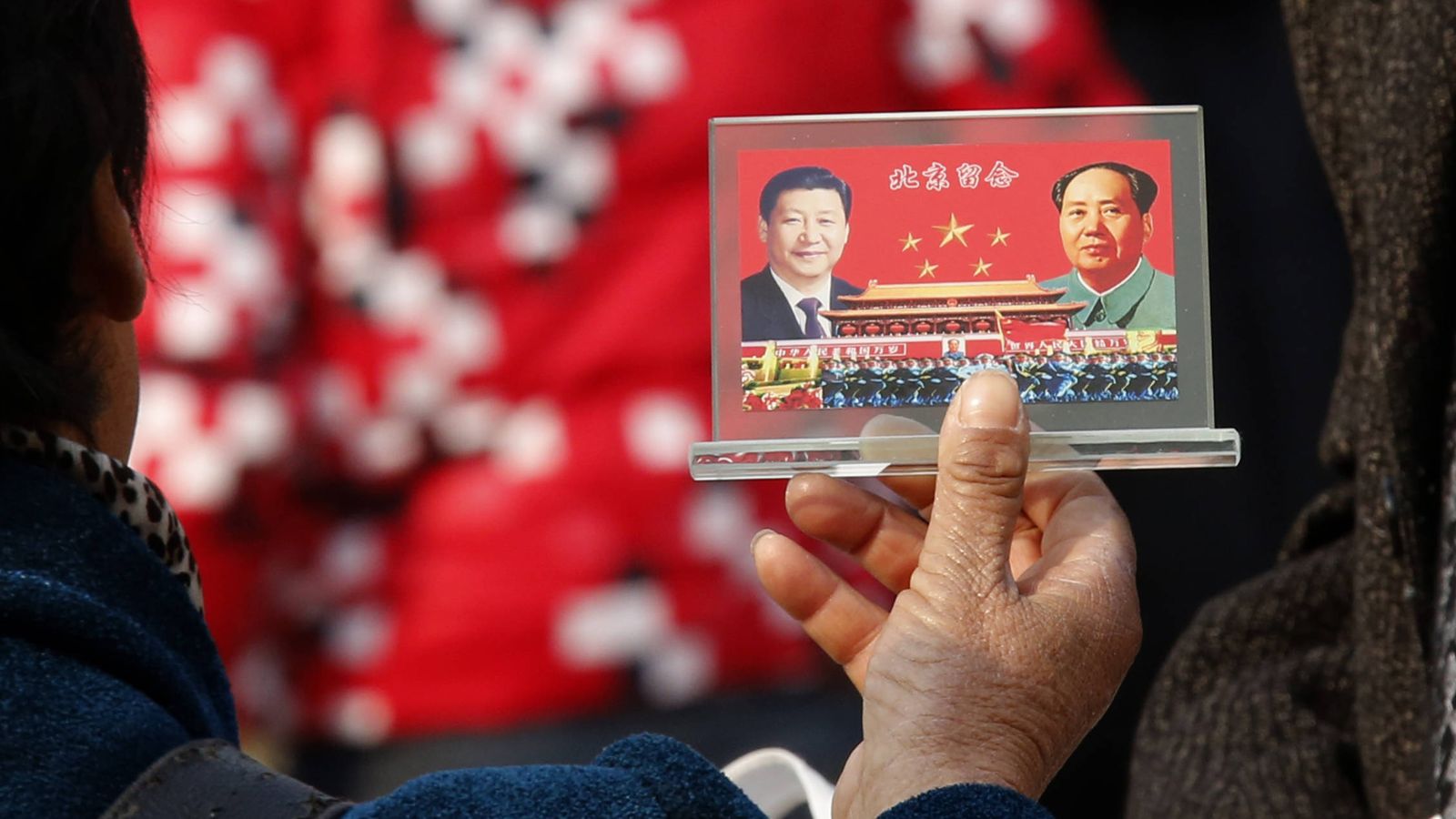 Foto: Un vendedor callejero muestra un souvenir con las fotos de Xi Jinping y Mao Zedong en la plaza de Tiananmen de Pekín, en noviembre de 2013. (Reuters)
