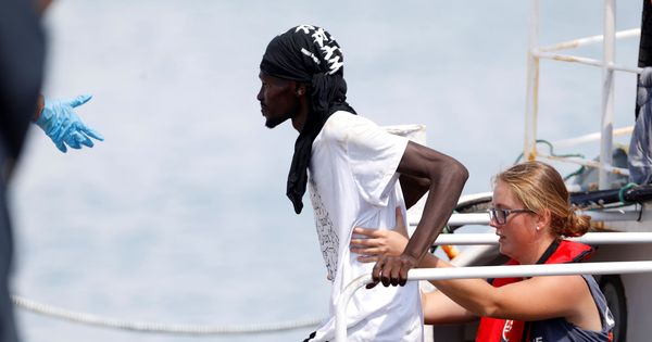 Foto: Un migrante, ayudado por una voluntaria en el puerto de Pozzallo, Italia. (Reuters)
