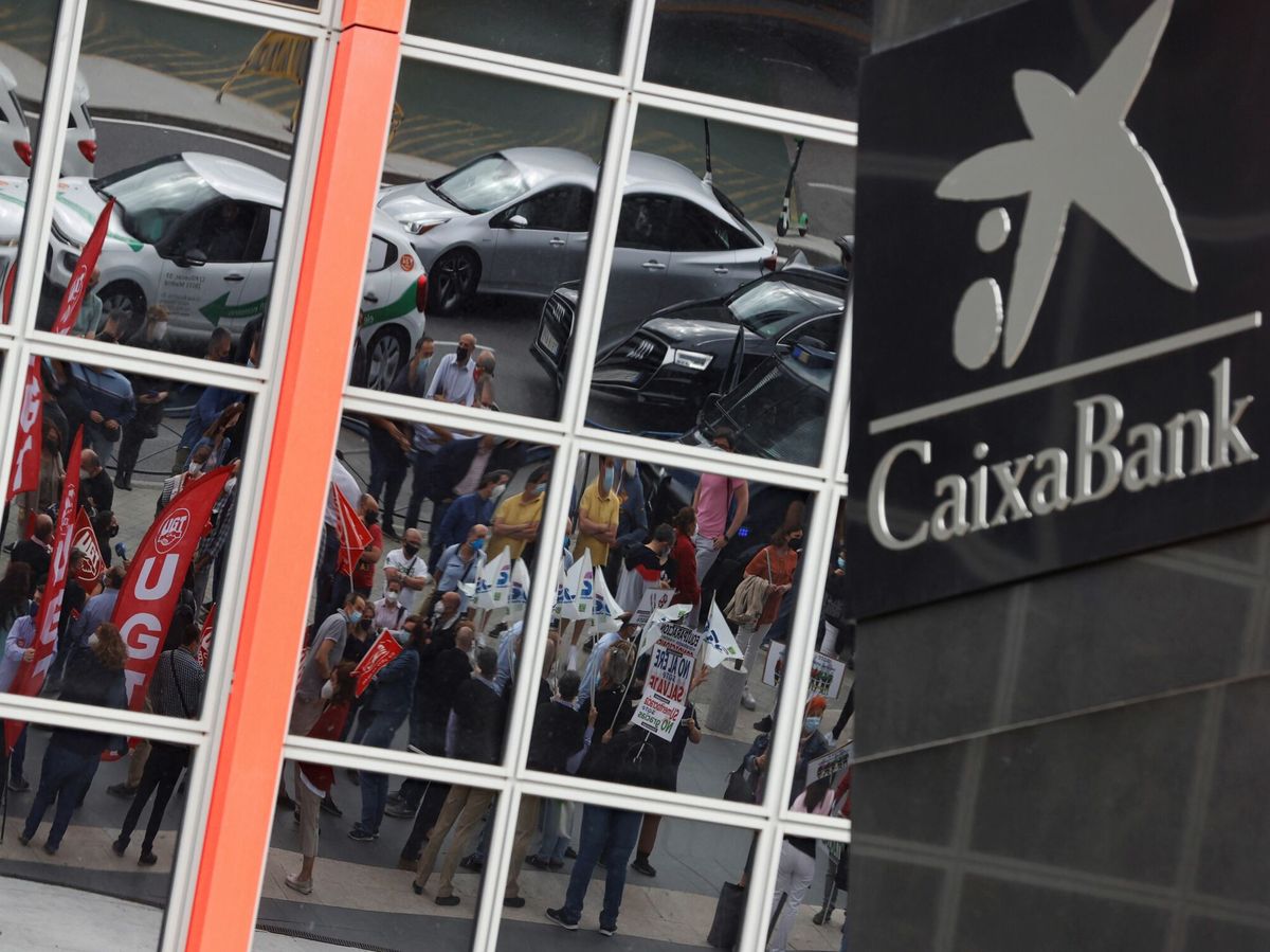 Foto:  Vista del logotipo de Caixabank este martes mientras se ve en el reflejo de una de las Torres Kio (EFE)