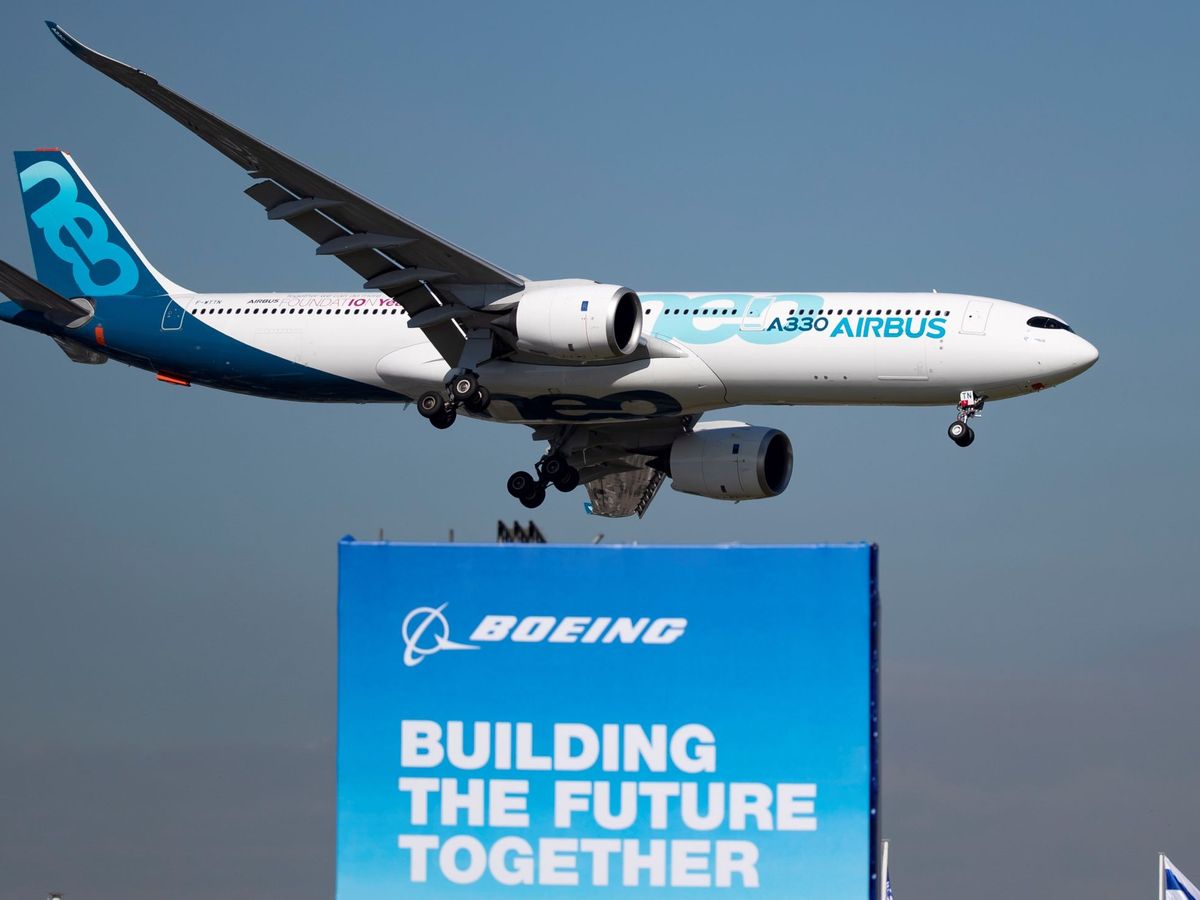 Foto: Un avión Airbus A330 Neo sobrevuela un cartel publicitario de Boeing. (EFE)