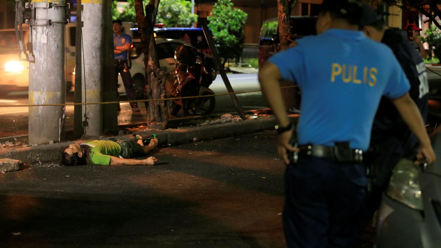 Policías observan el cadáver de un presunto vendedor de droga en Malate, el 29 de agosto de 2016 (Reuters)