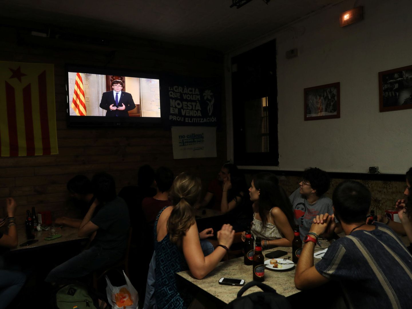 Un grupo de gente atiende en un bar al discurso del presidente de la Generalitat, Carles Puigdemont. (Reuters)