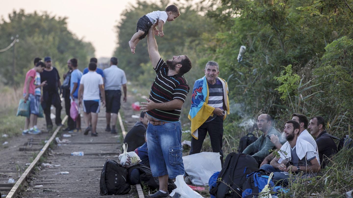 Un refugiado que espera para cruzar a Hungría juega con su hijo en la frontera serbia. (Reuters)
