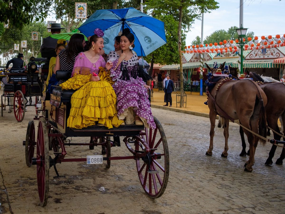 Foto: Dos mujeres vestidas con el traje típico flamenco a bordo de un carruaje (EFE/Julio Muñoz)