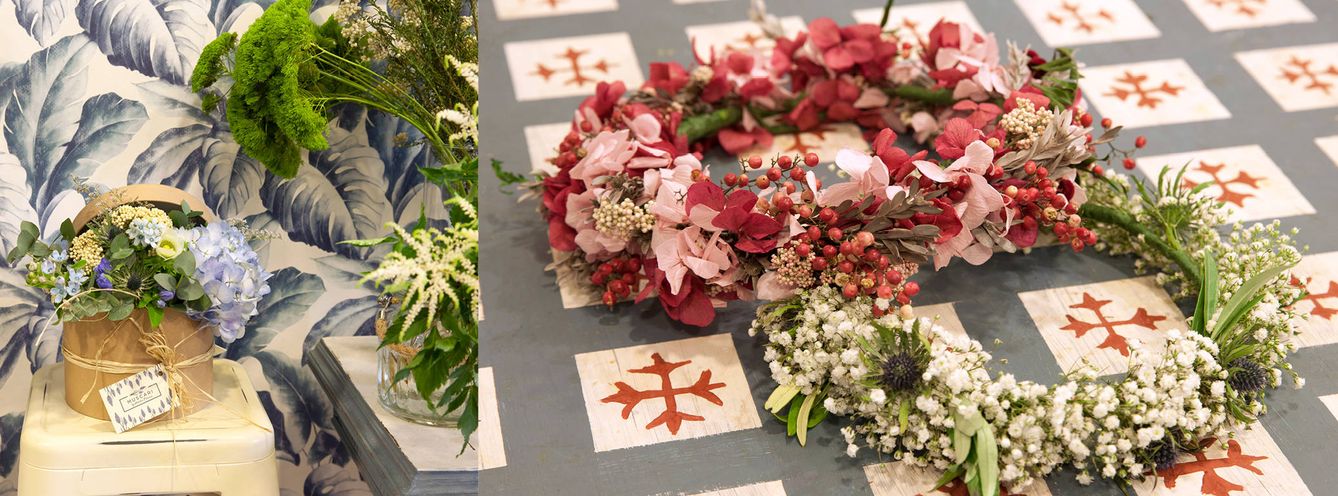Dos encargos de coronas de flores preparadas para entregar a sus clientes sobre una mesa pintada a mano por la propia Natalia.