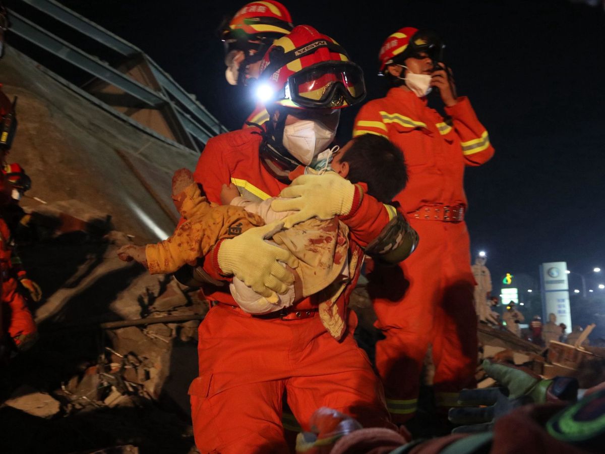 Foto: Un miembro de los servicios de rescate coge en brazos un niño que acaban de rescatar tras el derrumbe del edificio en Quanzhou, China, el domingo. (EFE)