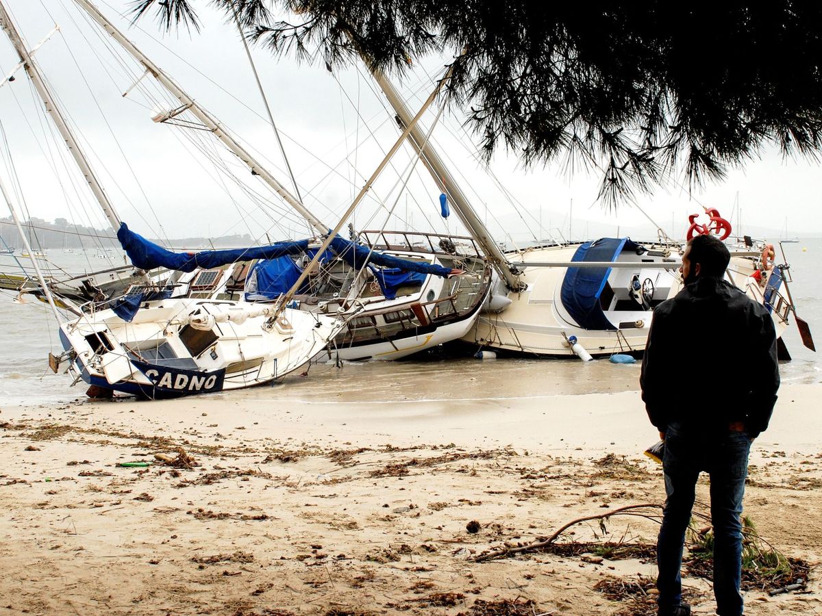 Foto: Un hombre mira tres de las embarcaciones varadas en la arena en el Port de Pollença (Mallorca). (EFE)